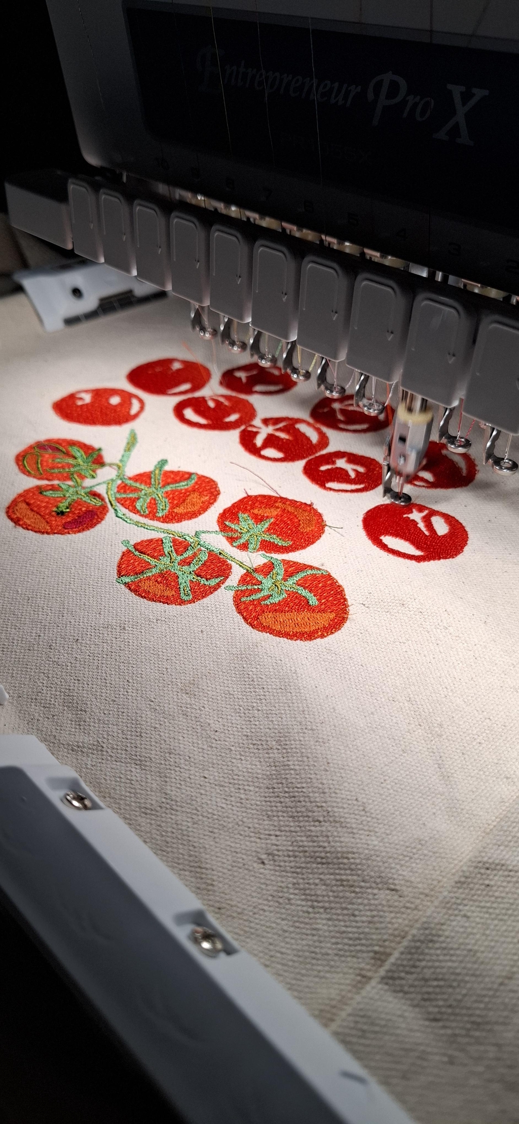 An embroidery file of vine tomatoes being stitched onto a canvas tote bag.