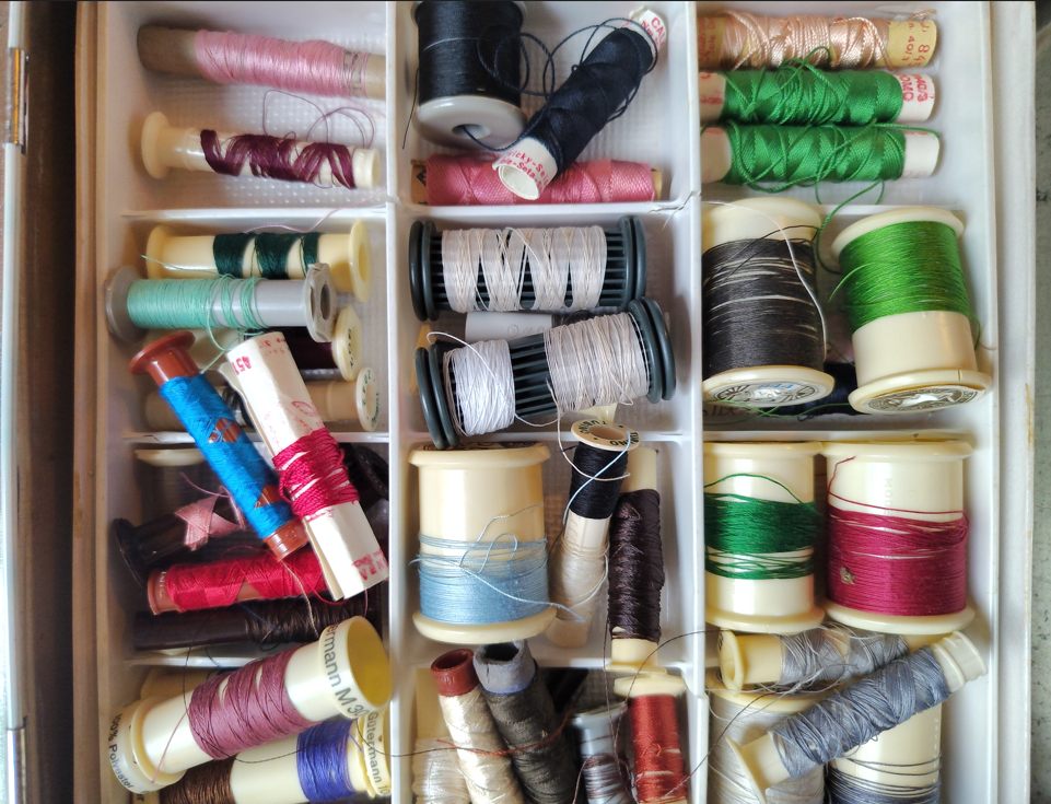 Bobines de fils à coudre colorés dans une boite.