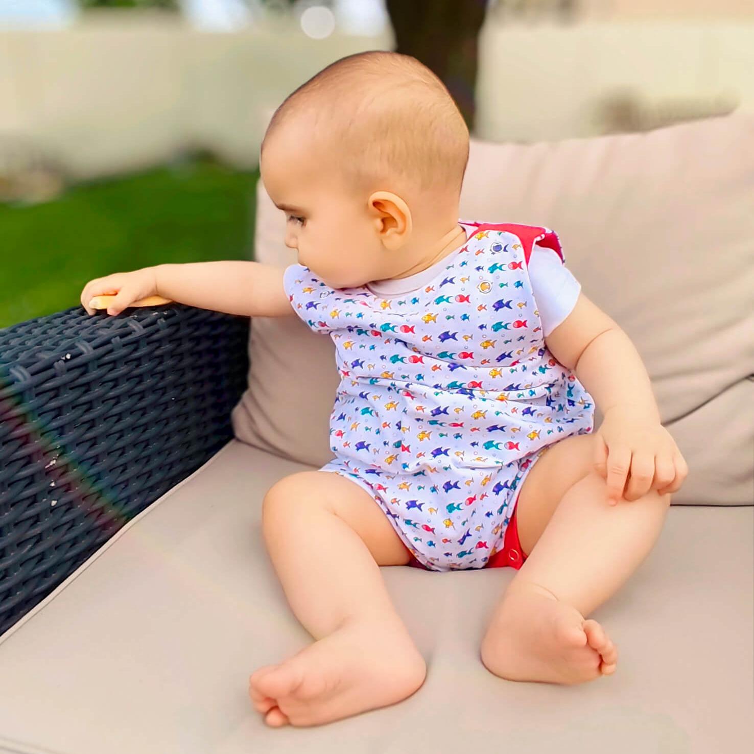 Salopette courte évolutive en coton bio GOTS portée par un bébé, motif Bloubloup blanc