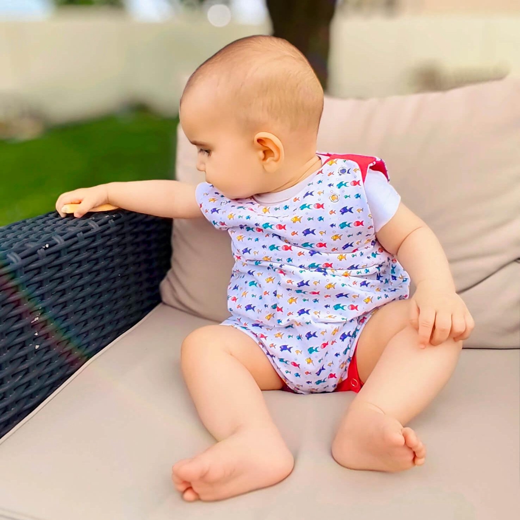 Salopette courte évolutive en coton bio GOTS portée par un bébé, motif Bloubloup blanc