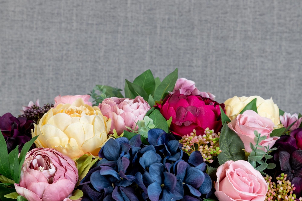 Artificial flower arrangement with colourful peonies and roses and hydrangeas