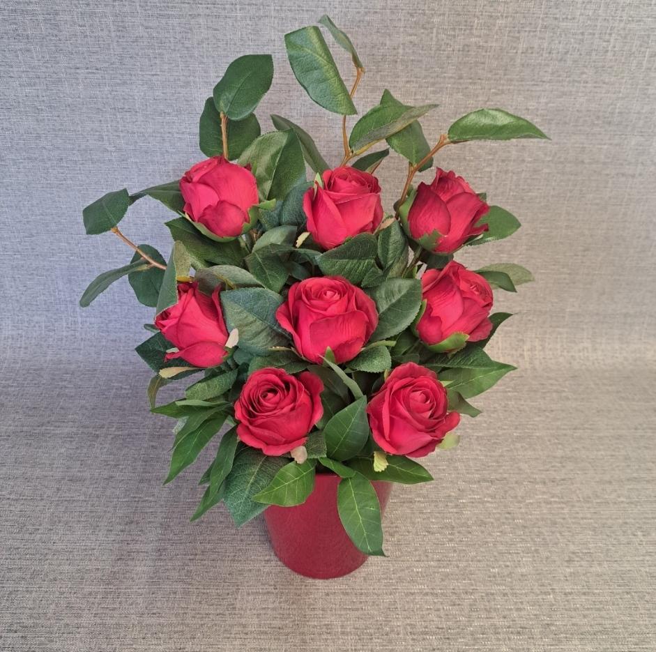 Artificial flower arrangement in a pot with faux red roses and foliage