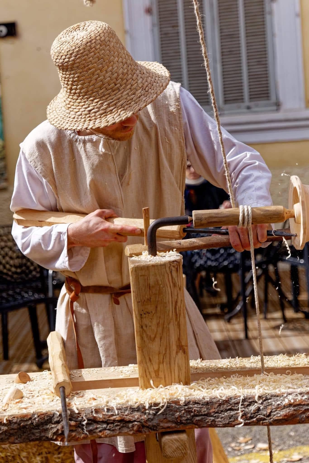 Un tourneur sur bois en costume médiéval façonne un bol sur un tour à bois traditionnel