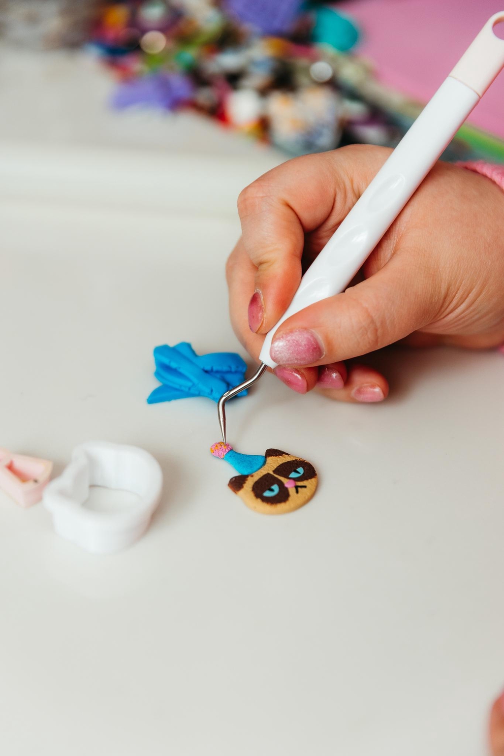 Picture of hand with tool fixing a clay image of a cat 