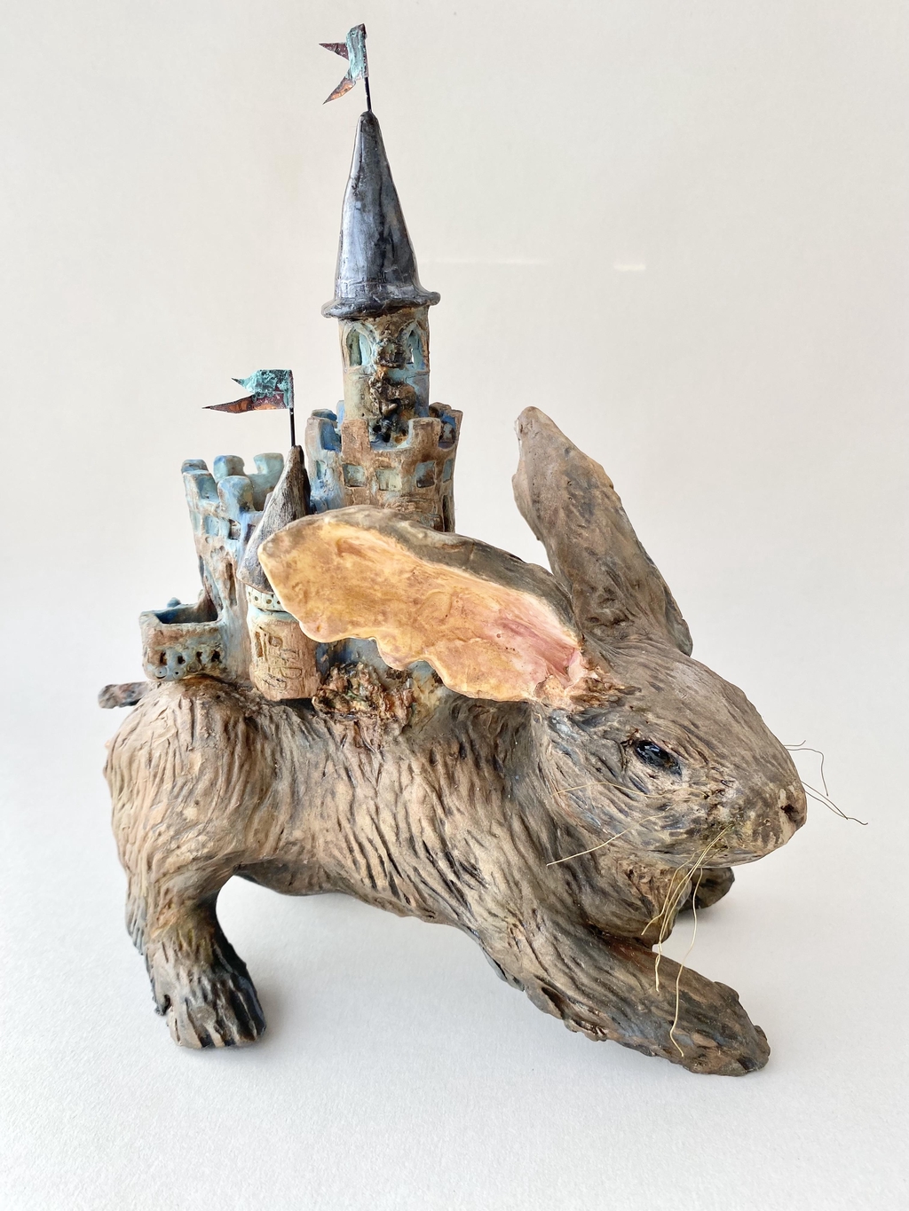Ceramic sculpture of a brown rabbit bearing a castle with turrets and a flying pennant