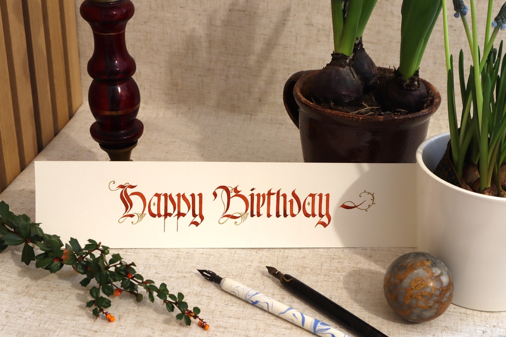 Handwritten Calligraphy 'Happy Birthday' in red and gold. Based on old German 'Fraktur' fond.
