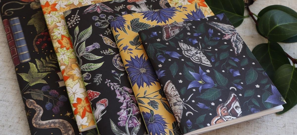 A collection of colourful hand bound sketch books with different paper designs and cartridge paper on the inside.