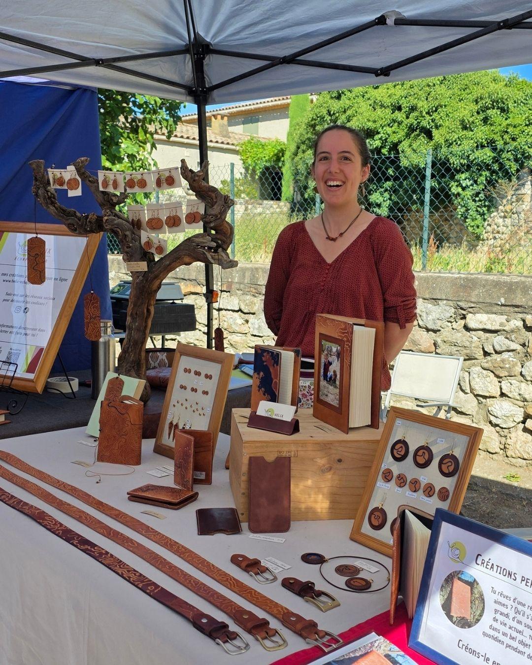 Photo de Claire Masquelier, créatrice de la marque Helix échappée cuir derrière son stand lors d'un marché.