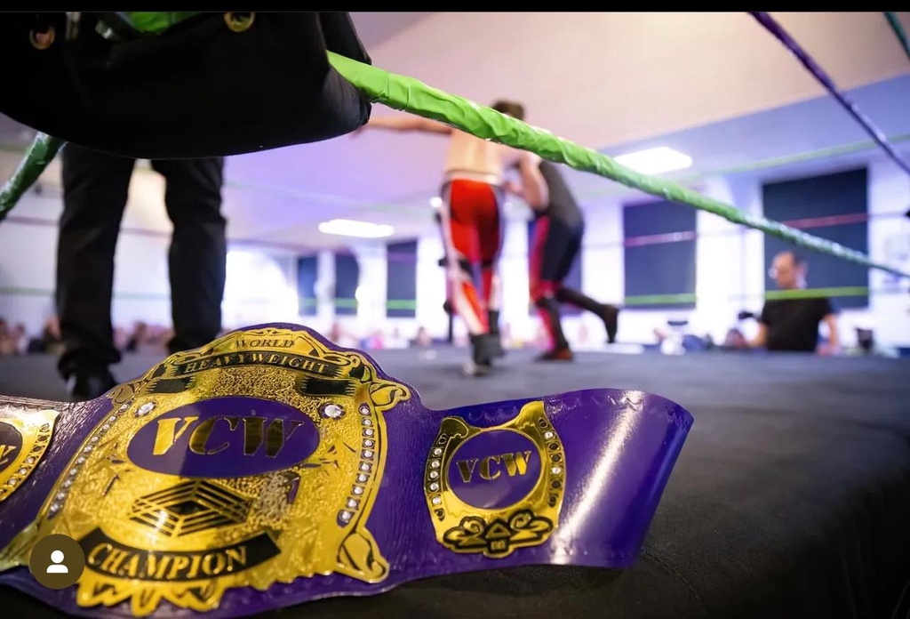 Three wrestlers stood behind a logo saying 'Pursuit for Glory'