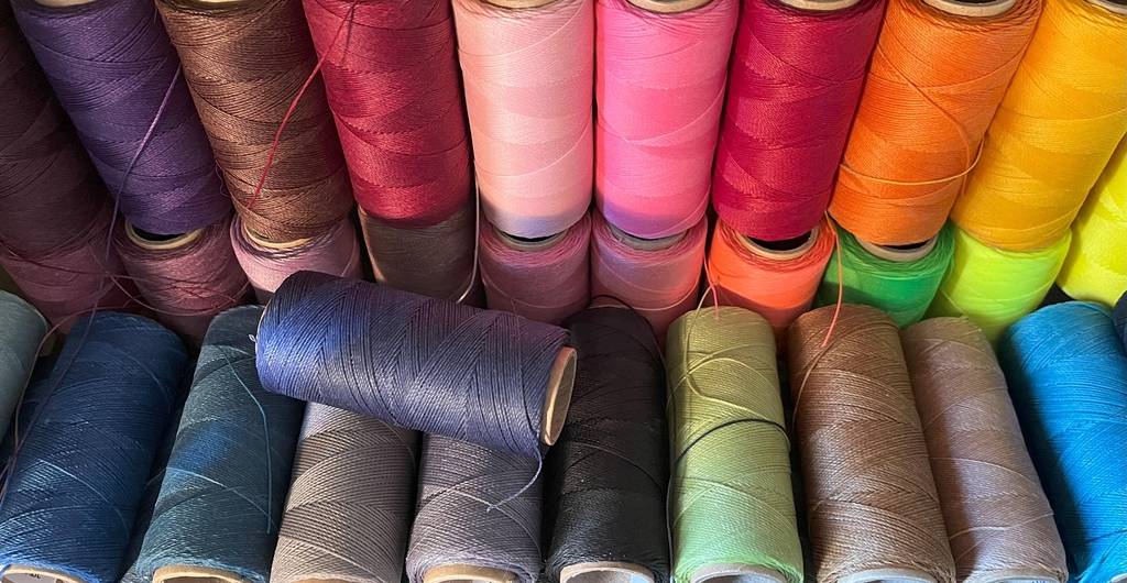 Bobines de fil ciré Linhasita multicolores utilisées pour la confection de bijoux de l'Atelier dans la tour