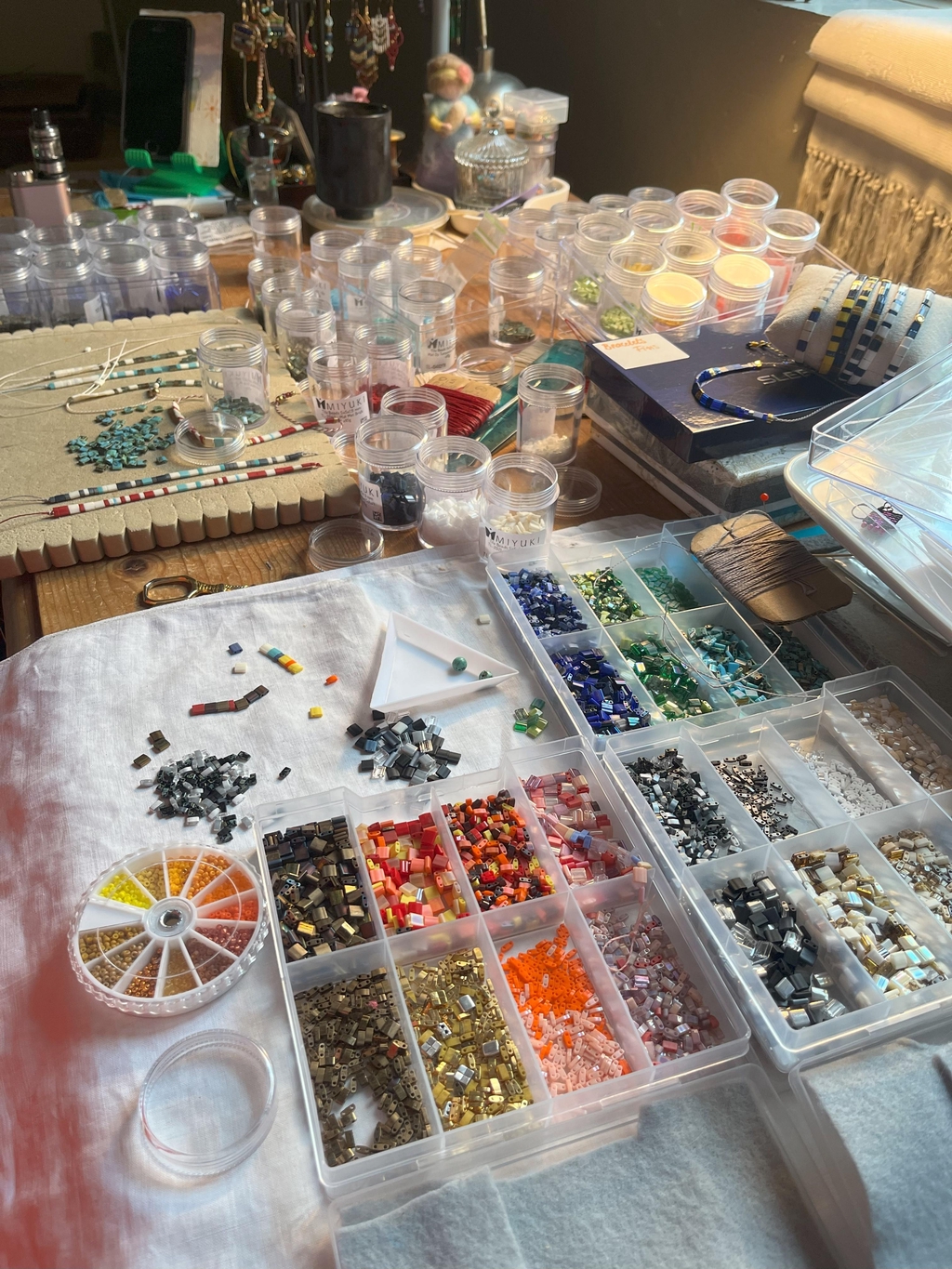 Vue de l'atelier. Palette de perles japonaises en verre Tila Miyuki triées par camaïeu de couleurs utilisées pour les créations de L'Atelier dans la tour.