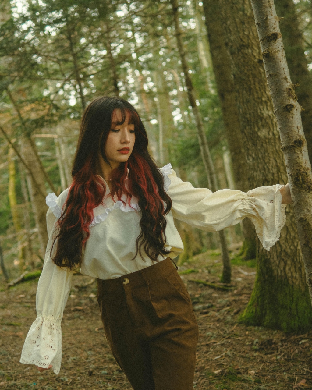 Jeune femme brune portant une robe aux couleurs pastel à volants et un panier, marchant dans la forêt