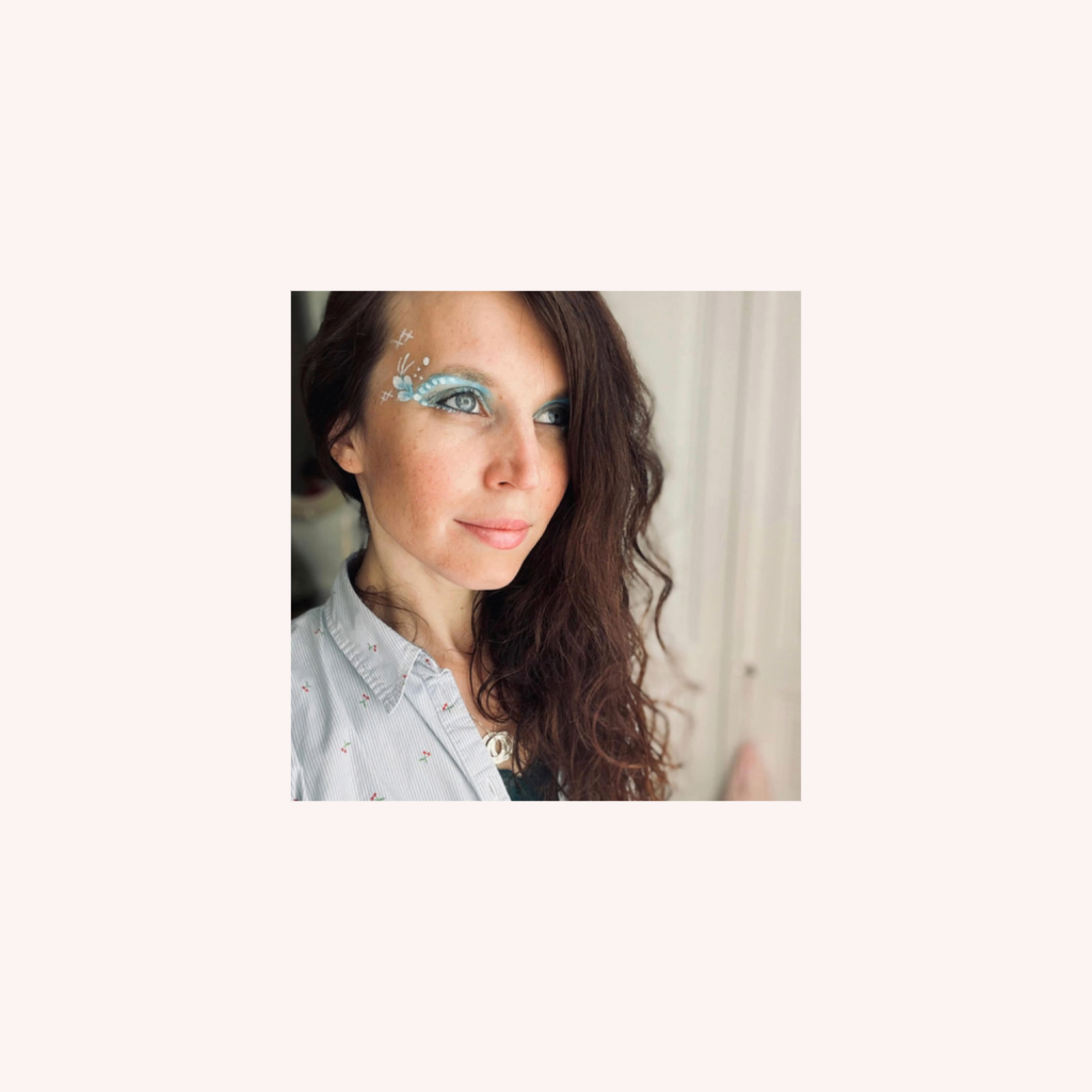 Photo de PeraRosa qui sourit et qui arbore un maquillage qui représente des roses jaunes et roses sur le côté droit de son visage.