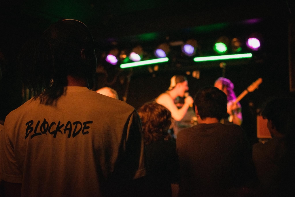 The alt-rock band Blockade performing at a live show, with a crowd cheering.