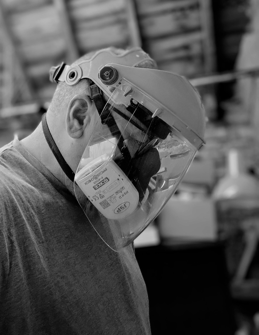 Craftsman working at a woodturning lathe in his workshop wearing breathing aparatus