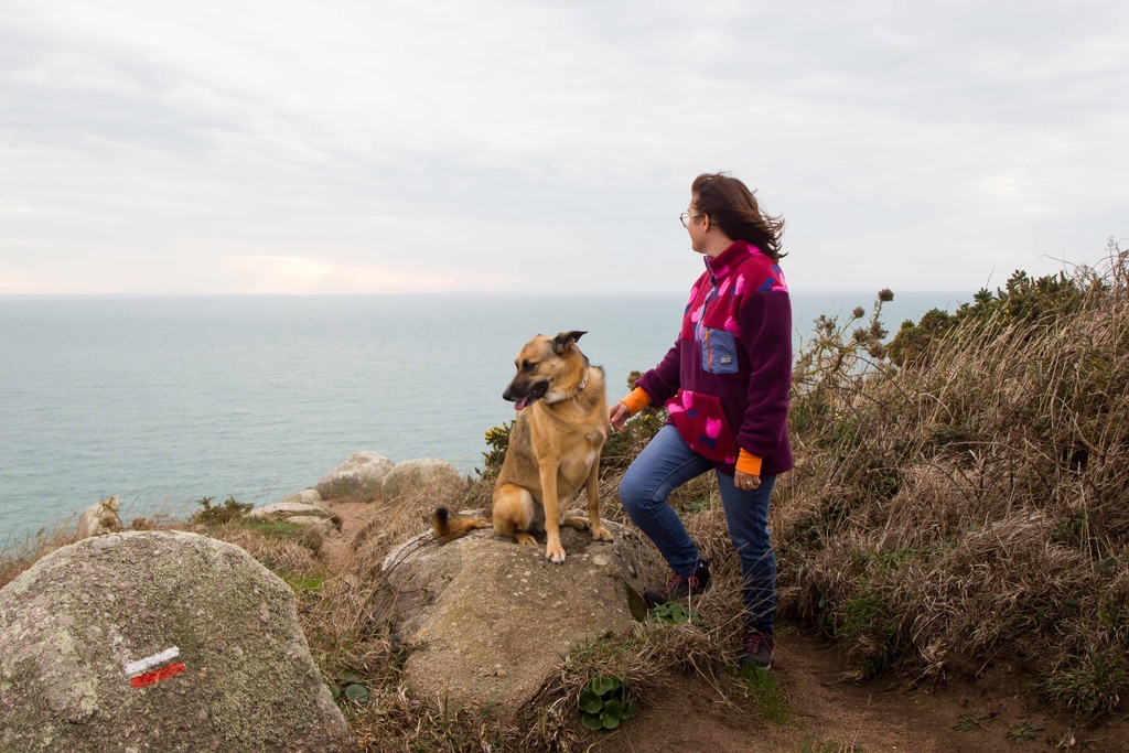 Femme et chien devant la mer avec une polaire rose fleurie