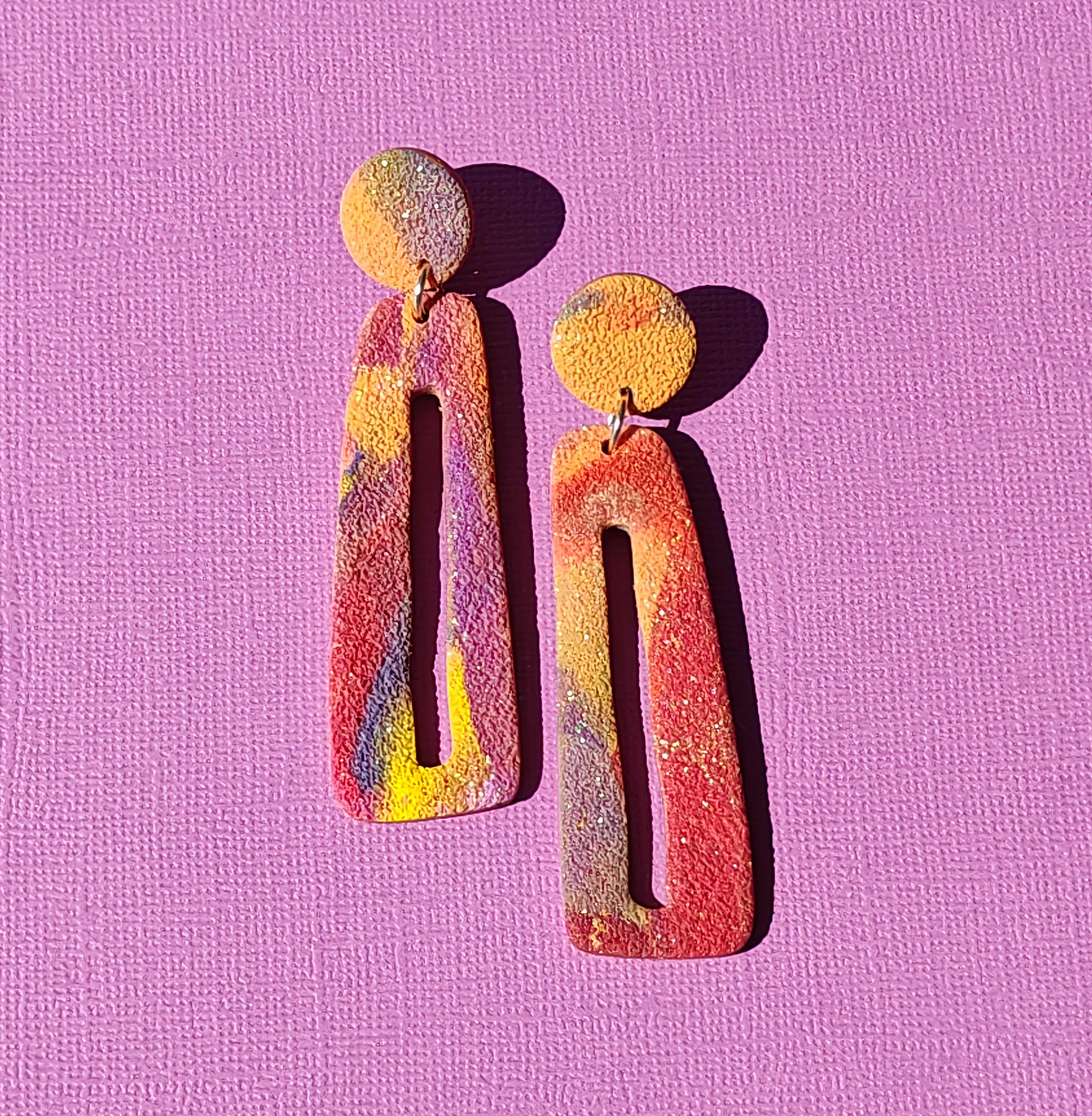Handgemaakte statement oorbellen uit de Aura collectie van Miel-oorbellen, in warme roze, oranje en paarse tinten met subtiele glitters.