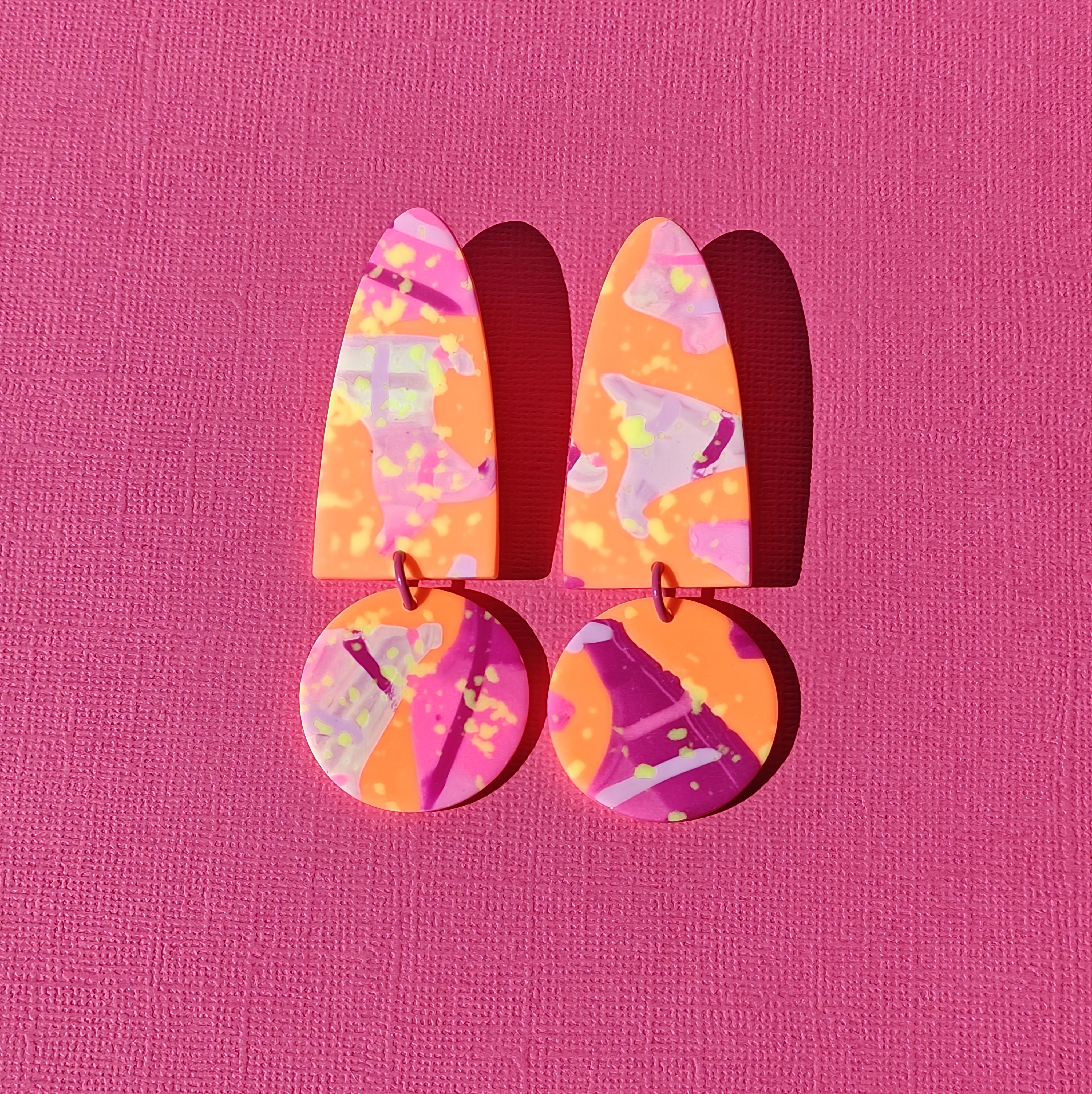 Handgemaakte statement oorbellen uit de Naranja collectie van Miel-oorbellen, in fel oranje, roze en lila met speelse neonaccenten en kleurrijke patronen.