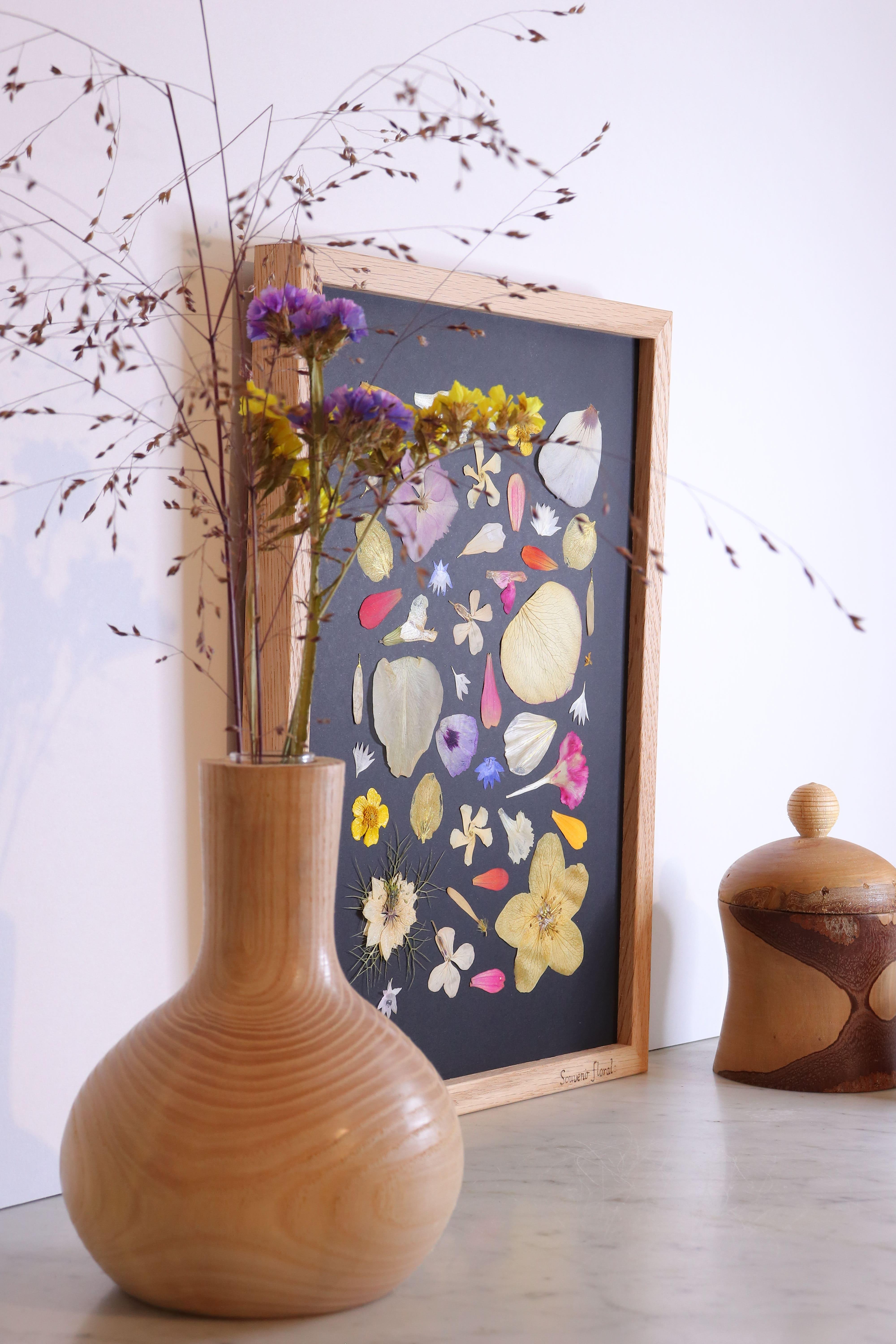 Composition florale délicate de fleurs pressées sur fond noir, accentuant les détails des pétales et des feuilles.