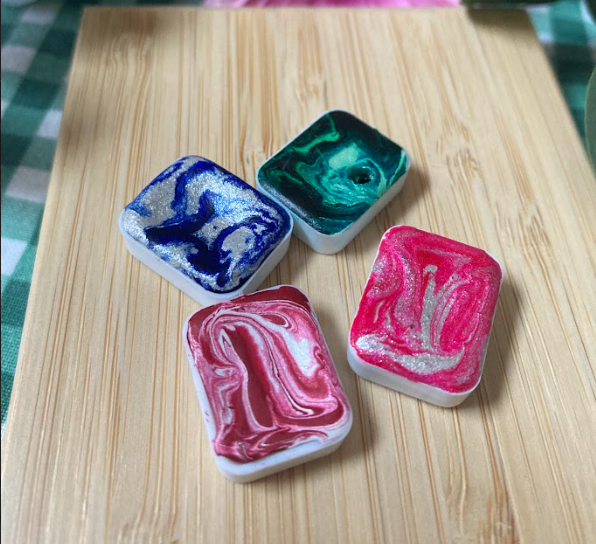 Les aquarelles avec un effet marbré et des reflets argentés ou dorés ! 

En effet, dès les premières couleurs que j'ai fabriquées, j'avais envie de pigments intenses en mêlant de l'argenté ou du doré. C'est chose faite ! La manière dont je broie et mélange les pigments laisse apparaître de jolies marbrures qui rendent chaque godet d'aquarelle uniques ! Une invitation à rêver et illuminer vos œuvres !