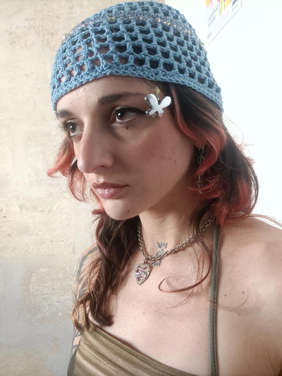 bonnet en crochet beige avec un motif de lapin blanc sur le côté, posé sur une table en marbre verte