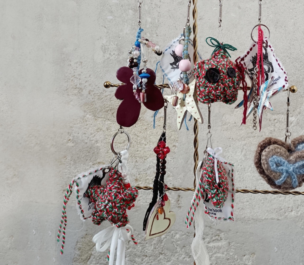 Présentoir à bijoux doré en forme d'arbre de noël présentant plusieurs porte clés ou charms de sac à main en céramique, perles, chaînes et crochet