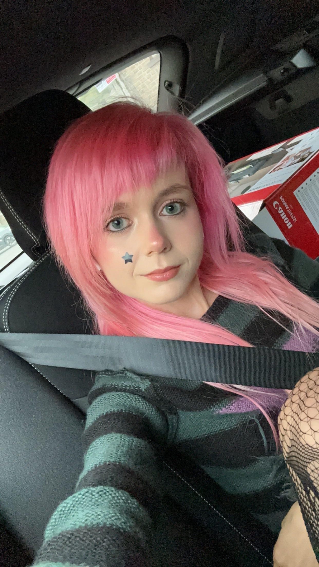 Customer wearing pastel pink scene hair wig that is long to their chest and side bangs in human hair blend wig.