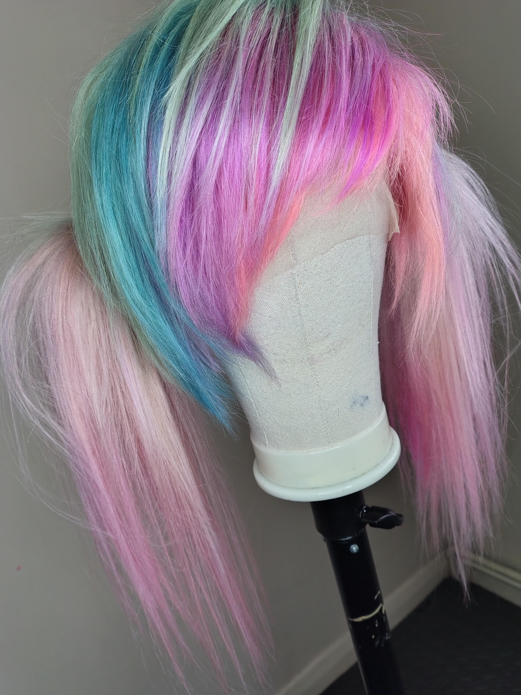 A picture of a pastel pink, blue, green and purple wig with pigtails in a scene hairstyle.