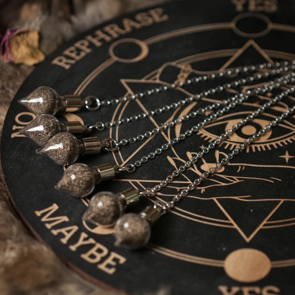 A selection of divination supplies such as handmade pendulums, spirit boards, and tarot cards