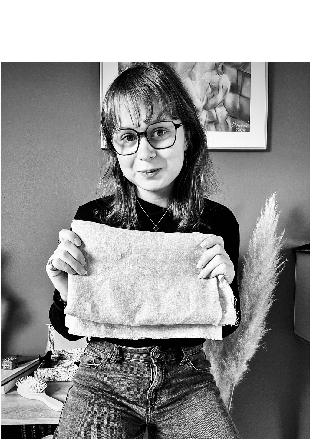 Jeune femme debout, qui tient en ses mains un tissu en lin. Le lin fibre avec laquelle L'Atelier du Vivant travaille pour créer des pièces durables.