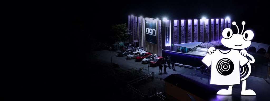 Fachada nocturna de NON The Club y Nony mostrando merchandising oficial