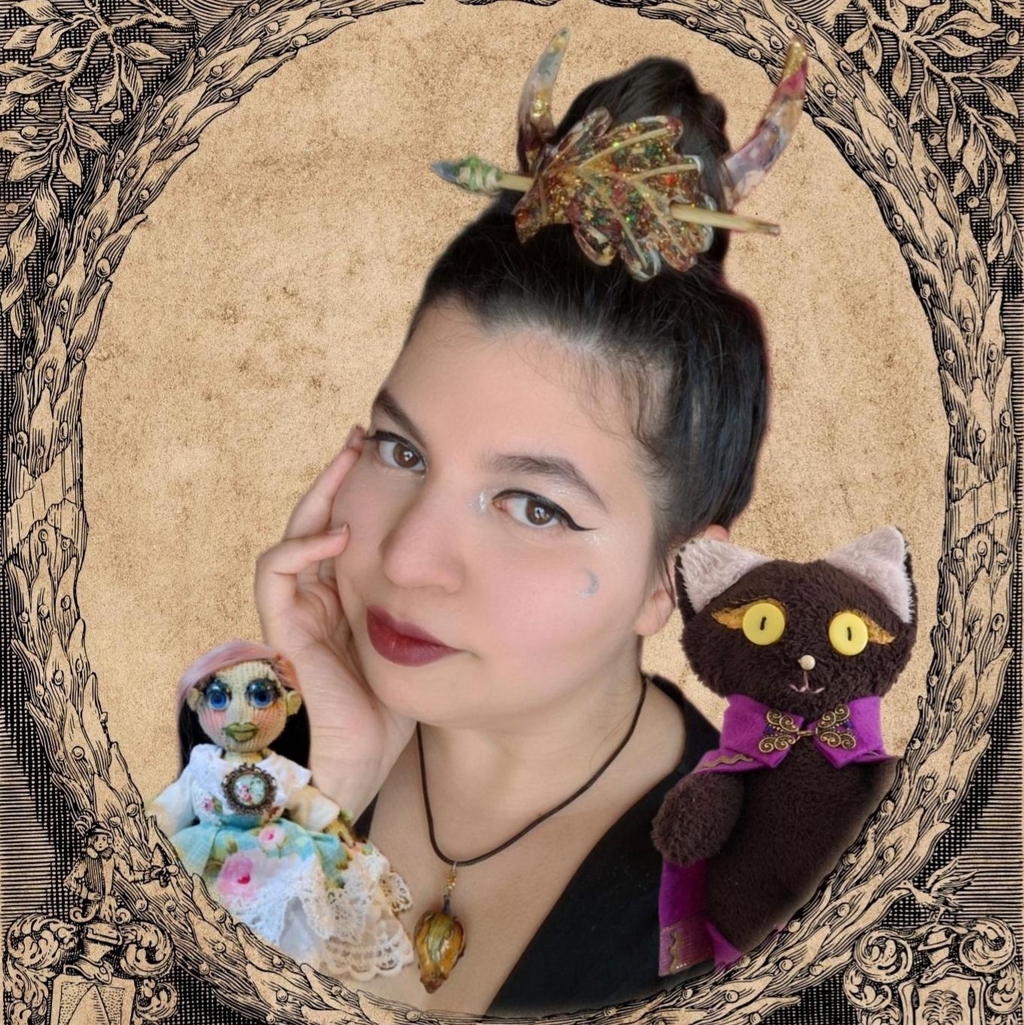 Bienvenue dans notre atelier en ligne !

Je suis Elizabeth, l’Enchanteresse. À ma gauche est Niena Della Notte, et à ma droite est Chocolat. Ensemble, nous formons l’équipe Della Notte.
Je suis l’artisane et l’artiste : je crée toutes sortes d’objets en résine et en tissu. Niena est le visage de l’atelier. Elle travaille sur les marchés et lors des événements. Quant à Chocolat, il nous accompagne dans la cueillette des fleurs que je fais ensuite sécher pour mes créations.
Avant d’être artisane, je dessinais et je peignais. Vous trouverez d’ailleurs des impressions de mes œuvres, ainsi que mes illustrations un peu partout (logo, blog, etc.). Puis, j’ai commencé à créer des lutines, des objets en résine et des peluches.
J’aime aussi restaurer d’anciennes peluches et poupées en tissu pour leur redonner vie. J’adore coiffer, surtout sur les marchés : les clients aiment essayer mes broches Lune ou mes Coif’feuilles, et j’ai toujours plaisir à les coiffer.
J’aime travailler avec les fleurs (même si je suis allergique au pollen) et j’intègre souvent des feuilles d’or, d’argent et de bronze dans mes créations.
Si vous avez des questions, ou si vous souhaitez collaborer avec moi pour une commande personnalisée, vous pouvez me contacter à :
houseofdellanotte@gmail.com