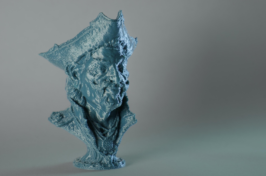 Impression 3D d'un pirate imaginaire. Couleur du modèle bleu-vert, fond gris avec une lumière très contrastante