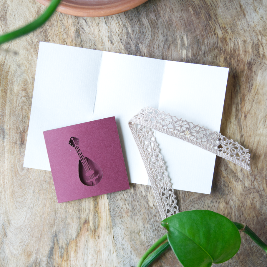 une mini carte présentant un Luth et un morceau de papier plié avec un ruban en dentelle pour le tenir