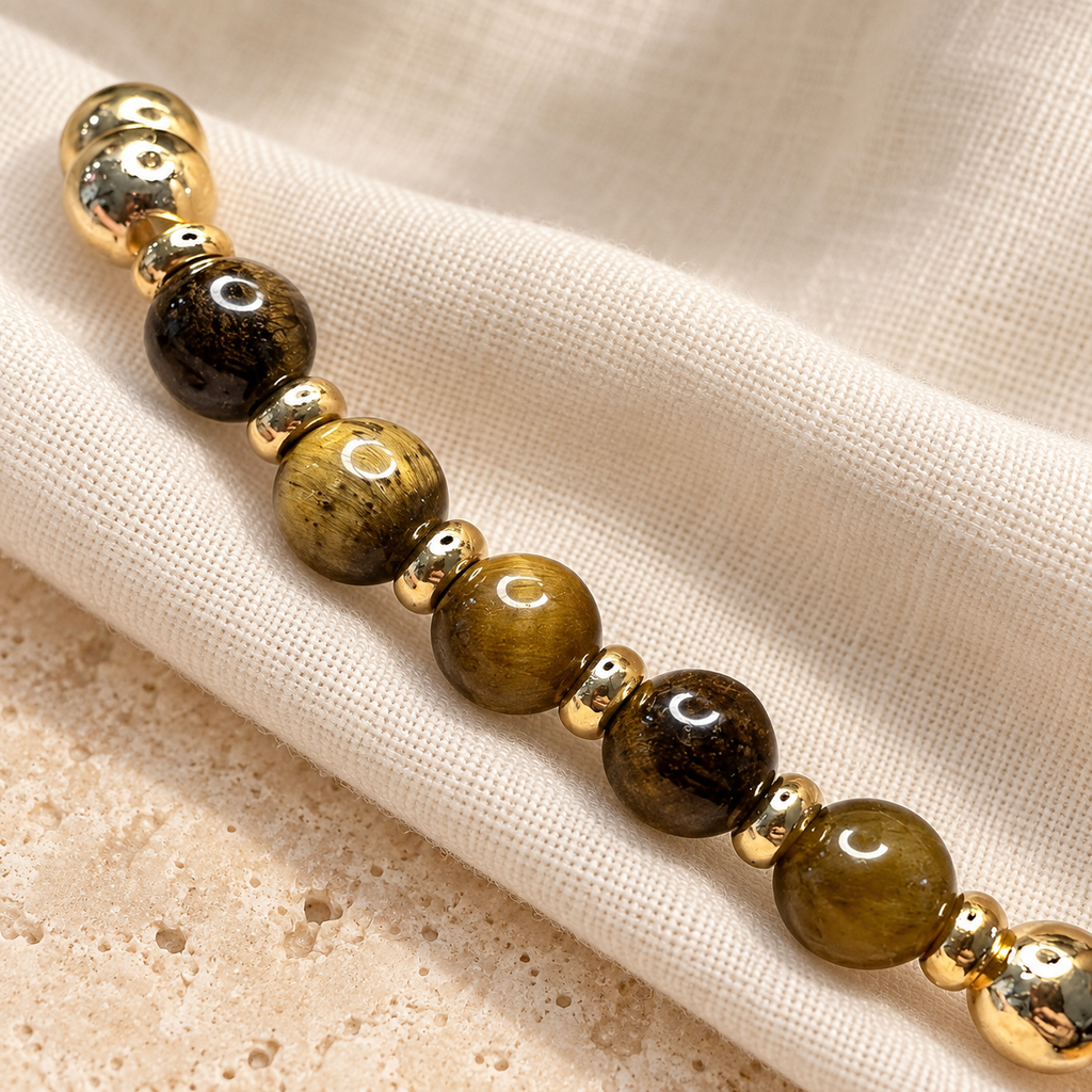 Nahaufnahme eines Club-Limone-Armbands aus Tigerauge-Perlen mit goldfarbenen Details
