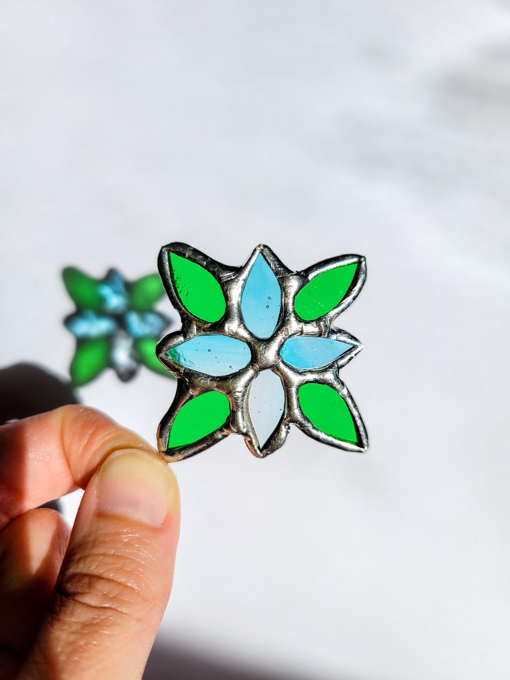 Pendentif vert et bleu en vitrail avec son reflet coloré