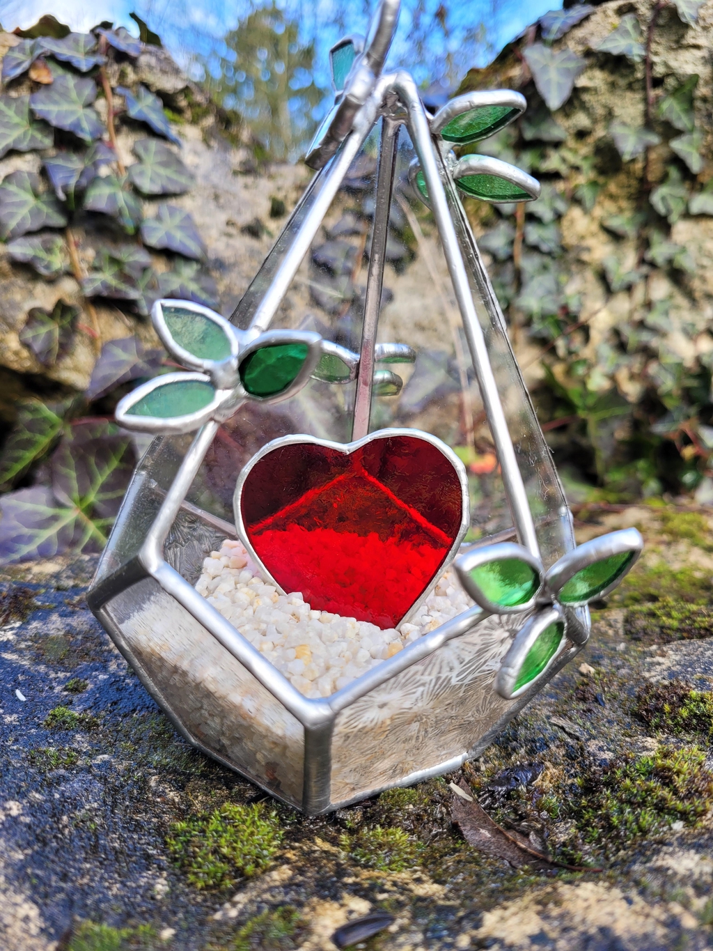 Terrarium en vitrail orné de petites feuilles vertes, avec un cœur rouge au centre