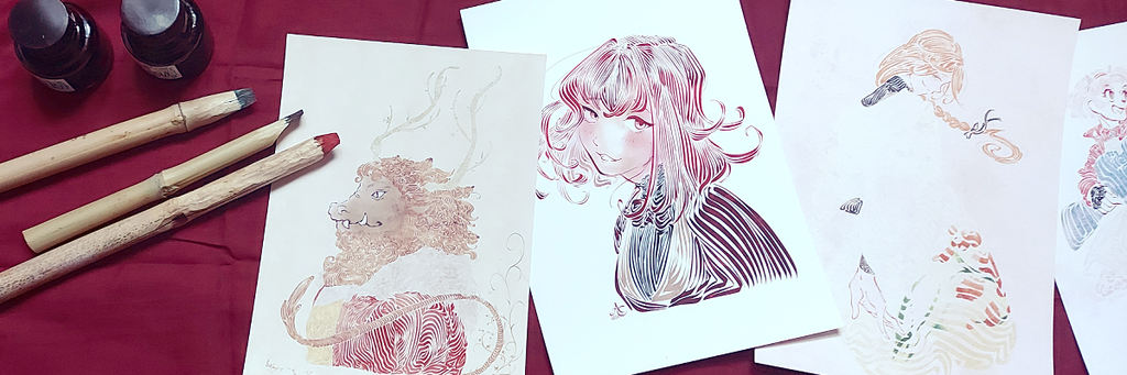 Encriers, calames déposés à côté de dessins calligraphiques illustrant le travail de A/C. Le tout posés sur une nappe rouge. 