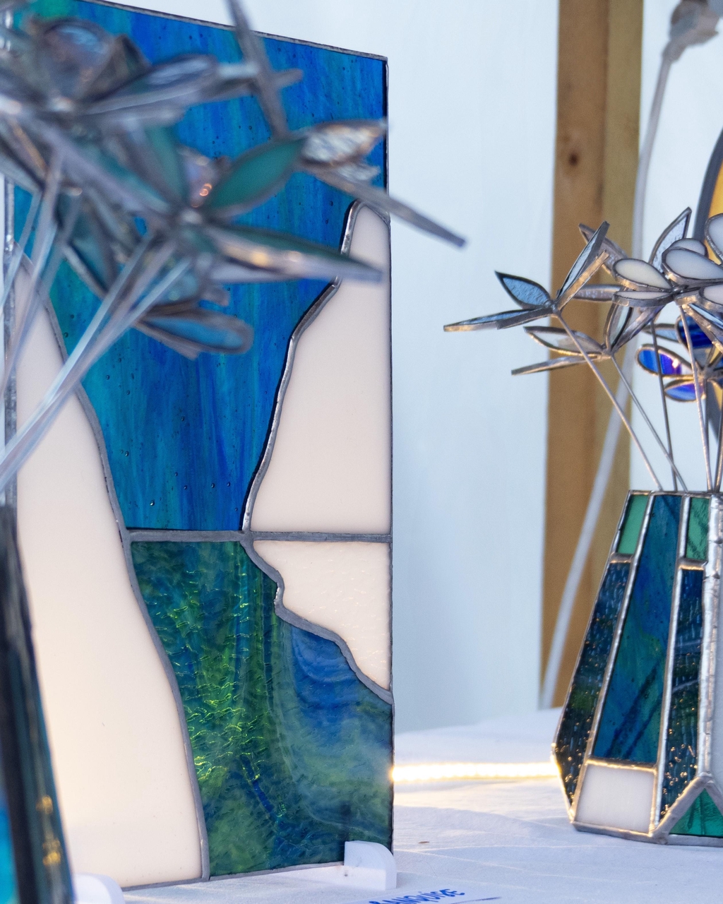 La collection Aurores boréales réunit des vitraux et objets lumineux en verre inspirés des paysages polaires et des phénomènes célestes du Grand Nord. Chaque pièce est réalisée à la main selon la technique Tiffany dans mon atelier en Corrèze, à partir de verres soigneusement choisis pour leurs nuances froides, leurs reflets irisés et leur capacité à capter la lumière. Vitraux décoratifs, vases et photophores évoquent les voiles lumineux des aurores boréales se reflétant sur l’eau, entourés de banquise et de silence glacé. Pensées comme des objets contemplatifs, ces créations transforment la lumière du jour ou celle d’une bougie en une ambiance douce, tamisée et apaisante. Les couleurs évoluent selon l’exposition, offrant une expérience visuelle toujours changeante, entre sérénité et émerveillement. Chaque pièce est unique : les reflets, les contrastes et les nuances varient naturellement selon l’environnement. Cette collection s’adresse à celles et ceux qui recherchent une décoration artisanale, poétique et lumineuse, mêlant vitrail contemporain, inspiration naturelle et atmosphère polaire, idéale pour créer un intérieur calme, élégant et inspirant.