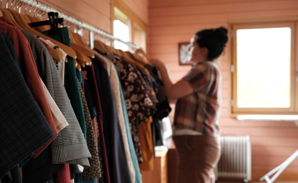 Photo de Manon Porre dans sa boutique avec un portant de vêtements