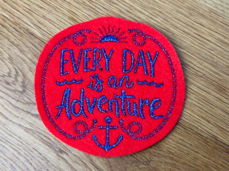 Runder roter Patch mit blauem Schriftzug: Every day is an Adventure