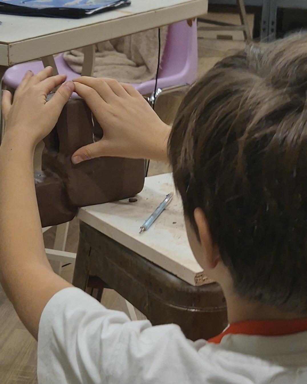 Photo de mains d'enfant et de sa sculpture en grès