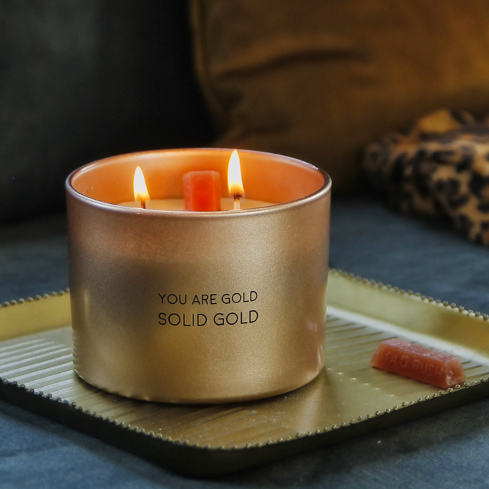 Brandende luxe geurkaars, My flame, in goudkleurige kaars op salontafel – huisparfum en wooncadeau.
