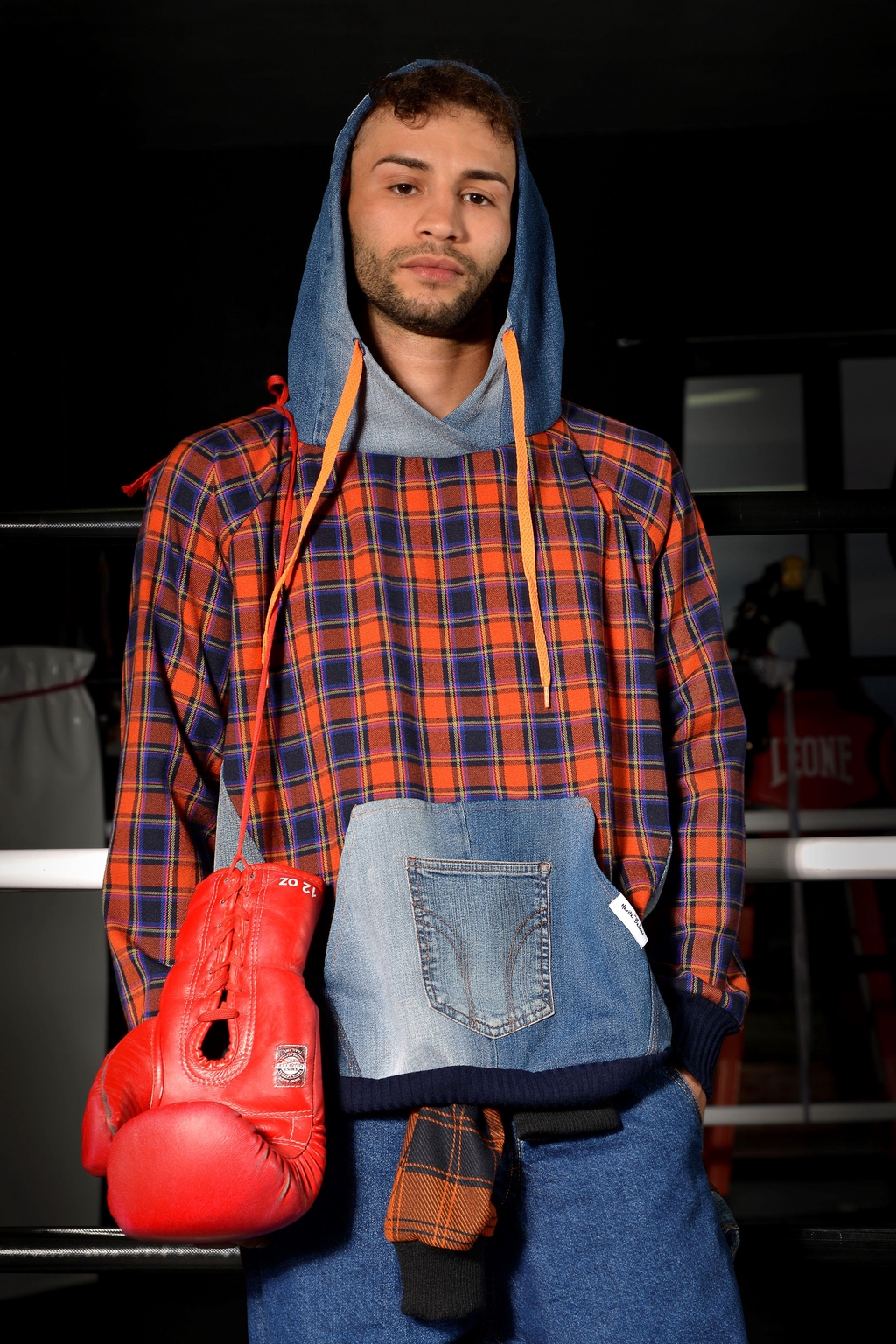 Matteo Lecca, campione italiano di pugilato, brand testimonial Marita Balàzs in posa atletica che indossa giacca in denim riciclato con dettagli punk e pantaloni neri, moda sostenibile unisex made in Italy - shooting professionale su sfondo scuro