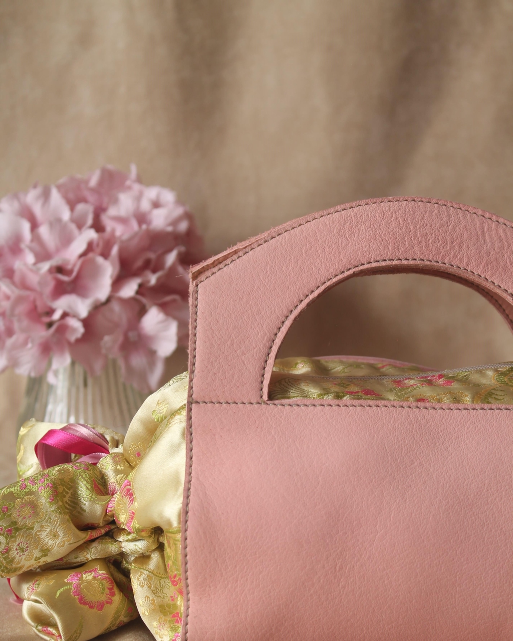 Sac à main papillote en cuir bi-matière veau rose poudré et tissu satin couleur champagne.