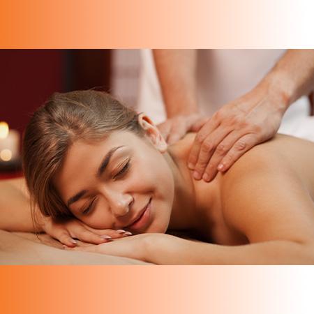 Eine junge Frau liegt entspannt auf einer Kosmetikliege und genießt eine Rückenmassage. Ihre halb geschlossenen Augen und das leichte Lächeln auf ihrem Gesicht zeigen tiefe Entspannung und Wohlbefinden. Die Hände der Masseurin sind bei der Massage am Rücken sichtbar. Im Hintergrund brennt eine Aroma-Kerze und schafft eine ruhige, angenehme Atmosphäre.
Dieser Text beschreibt das Bild und betont die entspannende Wirkung der Massage. 