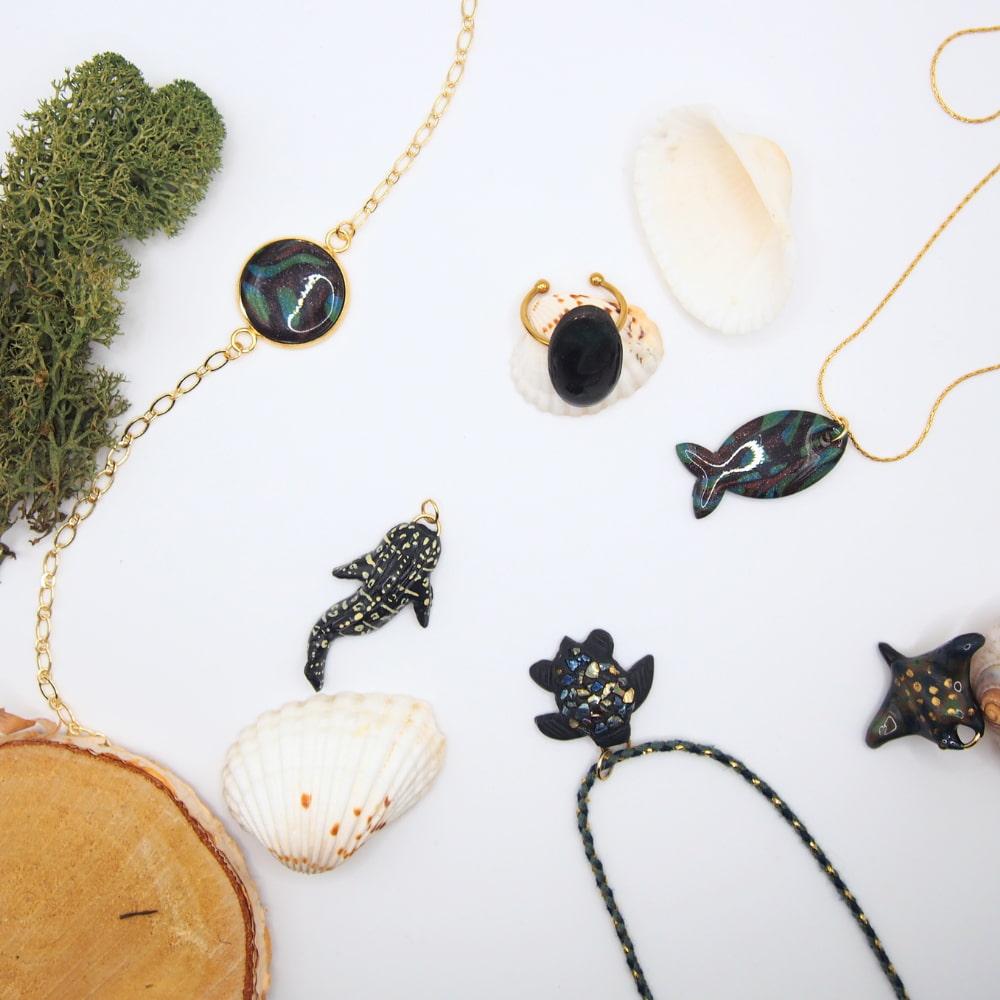 Collection de bijoux faits main en pate polymère sous forme de poisson, raie, requin tortues et baleines inspiré de la nature et l'océan, couleur bleu petrol vert des algues et marron des roches