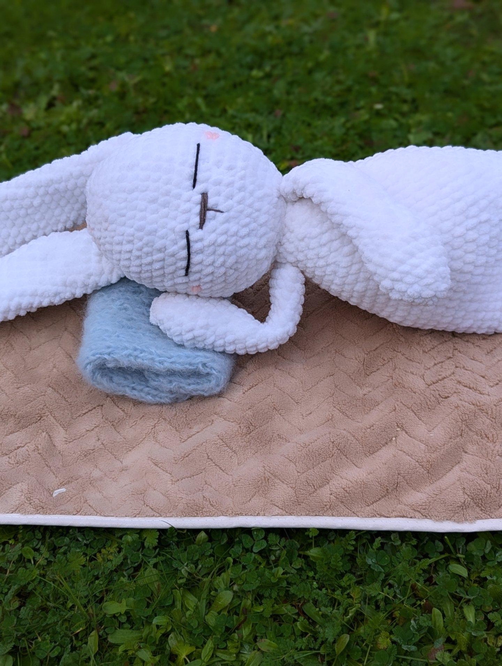 Doudou lapin fait main posé sur une couverture douce, symbole de la magie artisanale de Le Monde d'Anastasiia