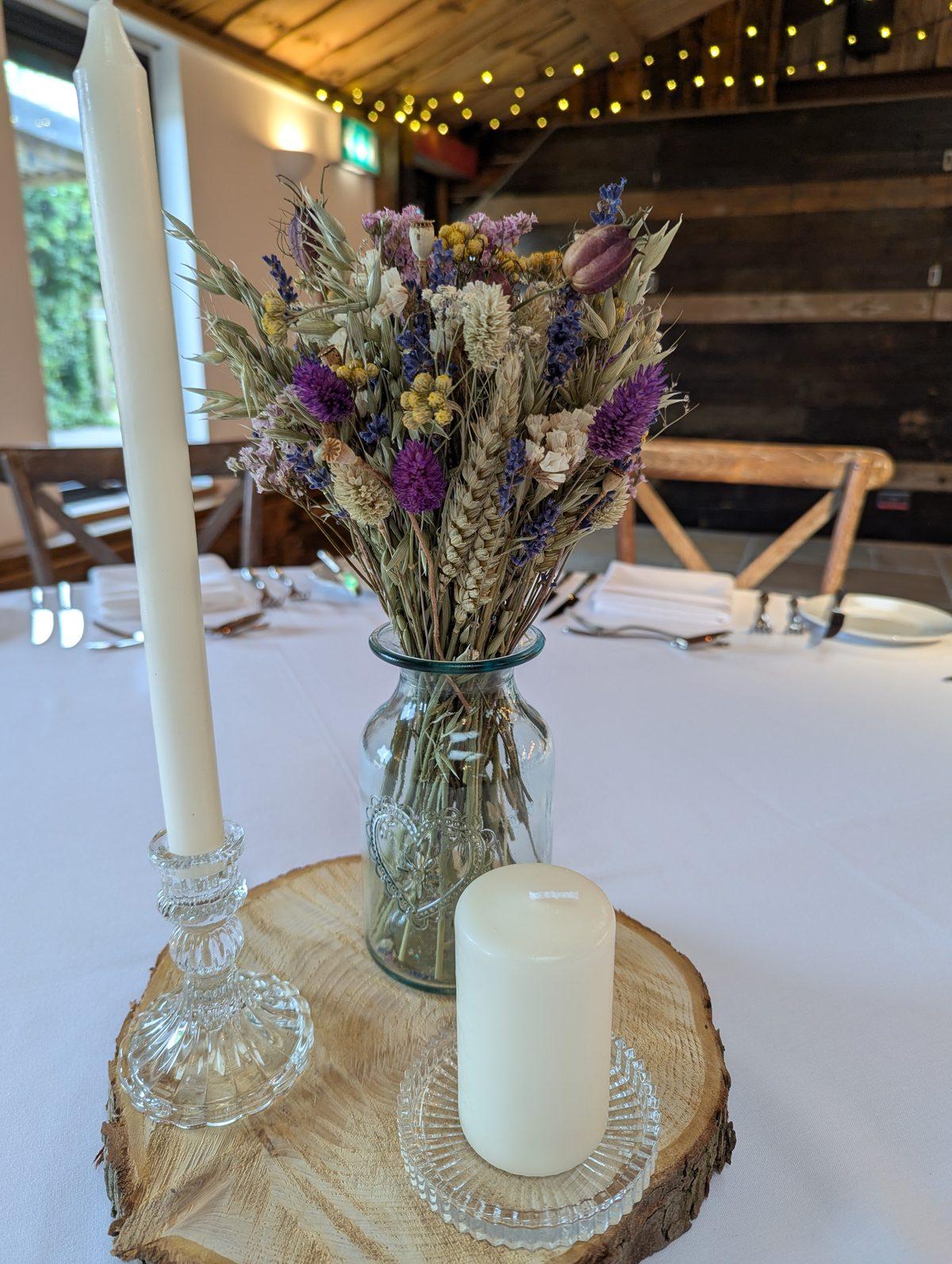 Dried flowers in a bud vase with candles in a wedding reception