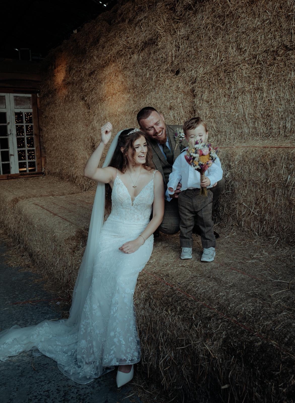 Photo of a family in a bard holding a dried flower wedding bouquet